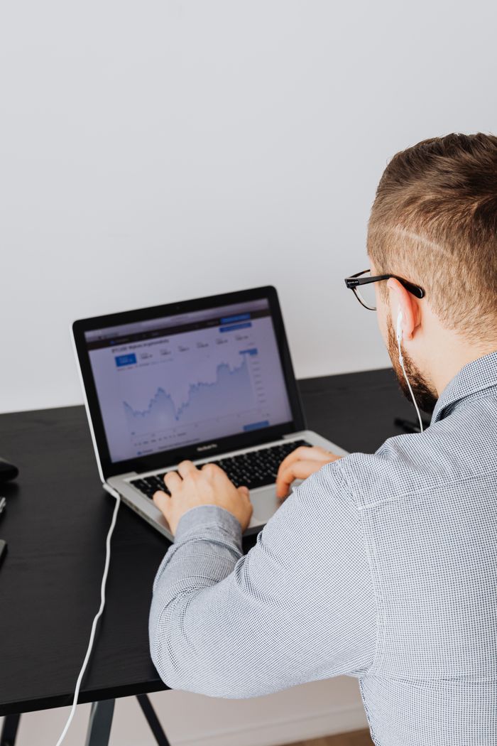 creative-03 A man uses a laptop indoors to analyze stock market trends graph on screen.