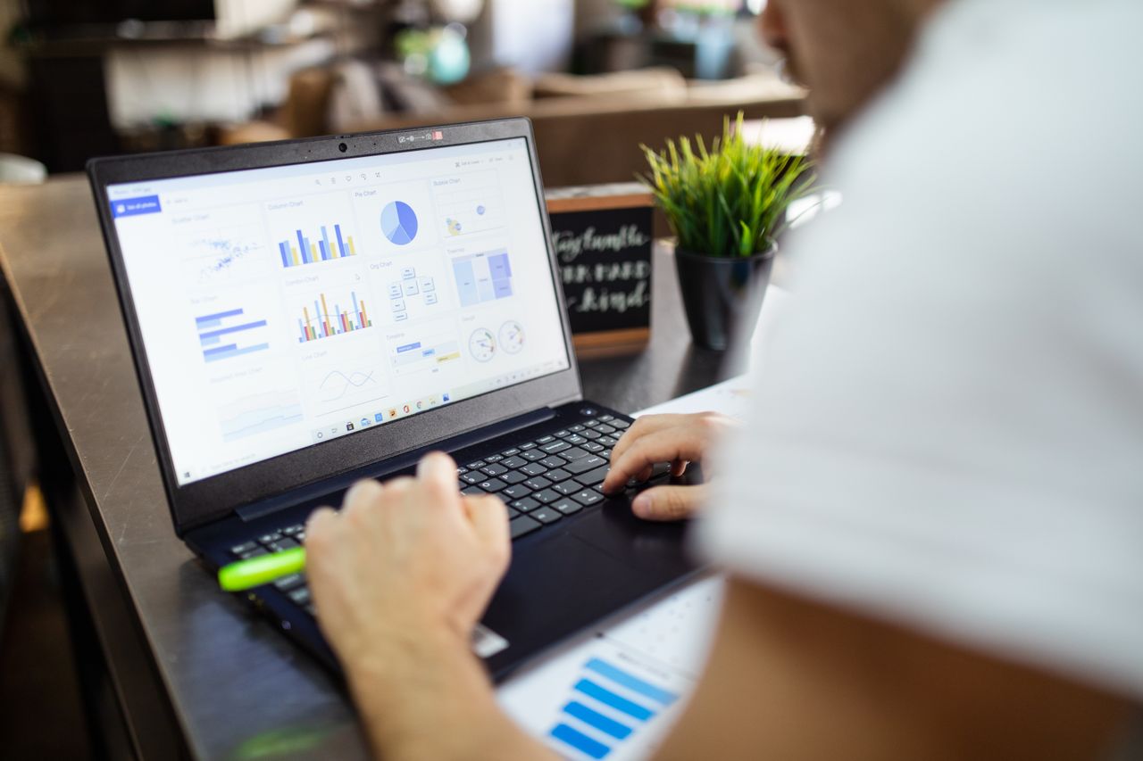 creative Focused business analysis with charts and graphs on a laptop in a modern office setting.